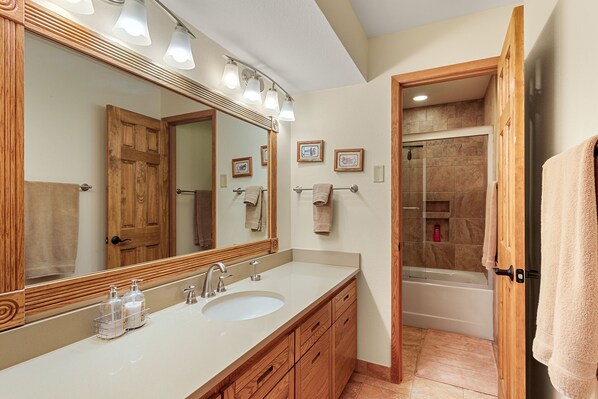A bathroom with a large mirror, two sinks, wooden cabinets, and a shower area. - Recently Remodeled 3 BR Condo, walk to the Peru Chair! (Keystone)