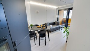 Una cocina moderna con zona de comedor, que incluye una mesa con sillas, un sofá y una planta en maceta.