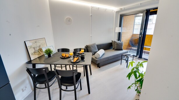 Un espacio habitable moderno con comedor, sofá y una mesita con productos para el desayuno.