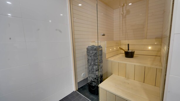 Un baño moderno con cabina de ducha de vidrio, un banco de madera y un perchero para toallas.