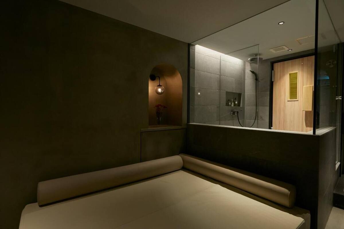 A modern bathroom with a glass enclosure, a bench, and a wooden panel.