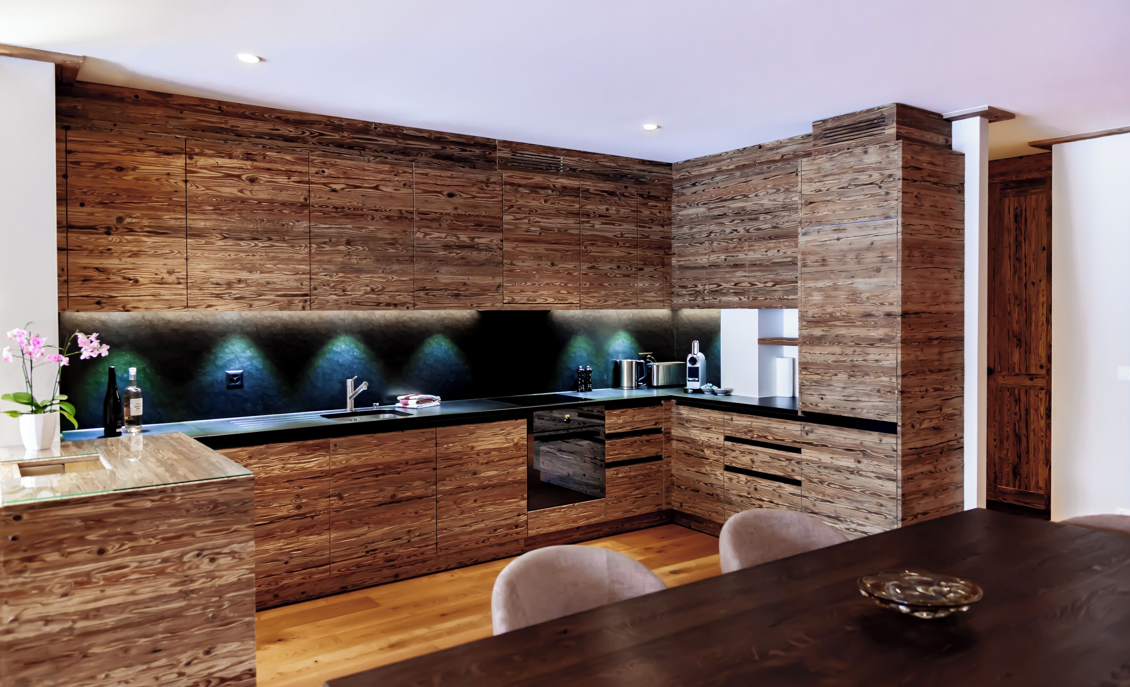 Una cocina moderna con armarios de madera, encimera negra y horno empotrado.