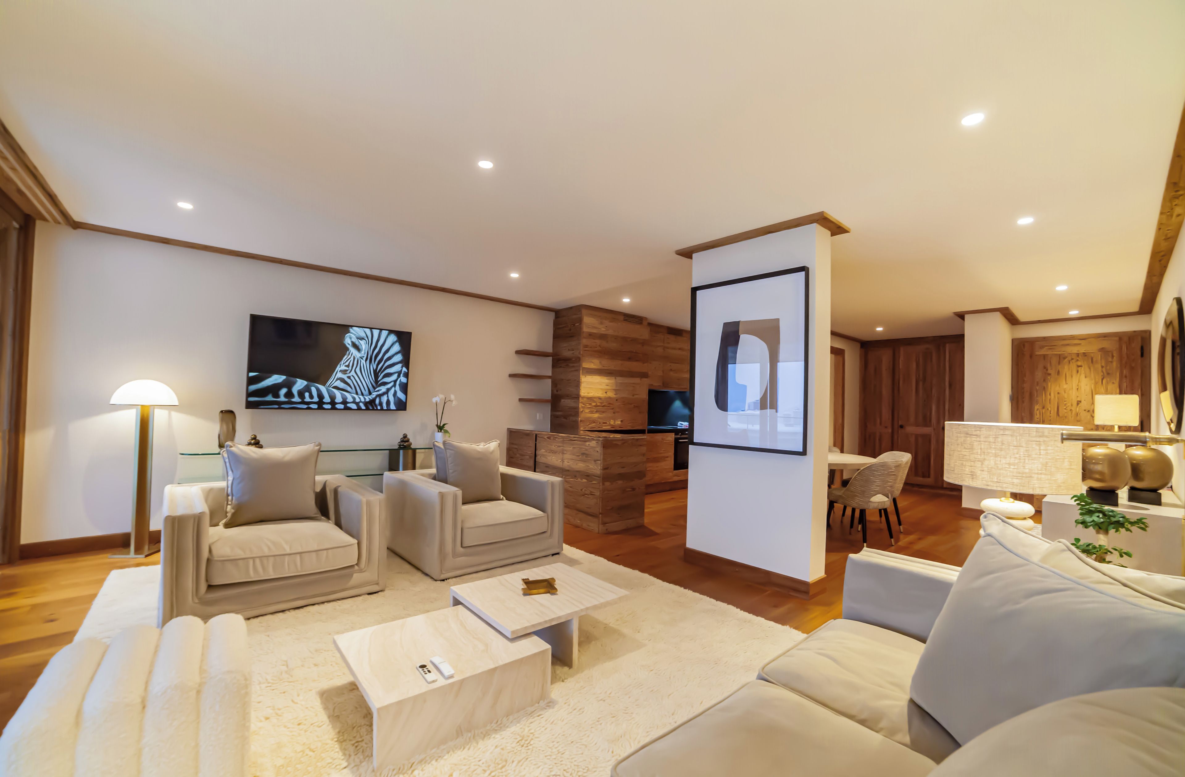 A modern living room with a flat-screen TV, two sofas, a coffee table, and a wooden accent wall.