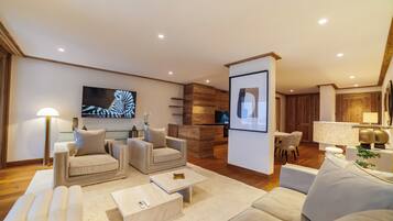 A modern living room with a flat-screen TV, two sofas, a coffee table, and a wooden accent wall.