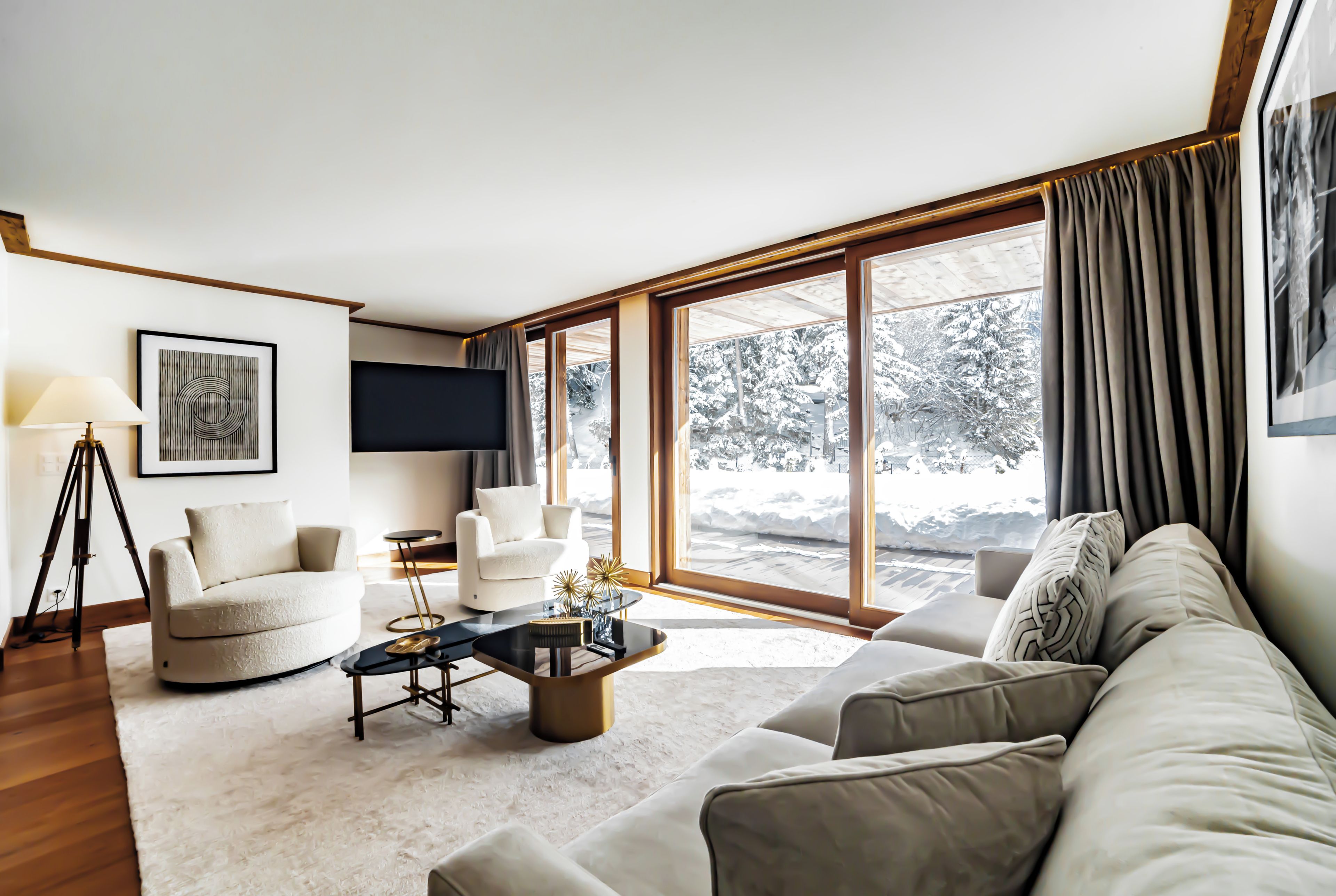 A modern living room with a sofa, armchairs, a coffee table, and a TV.