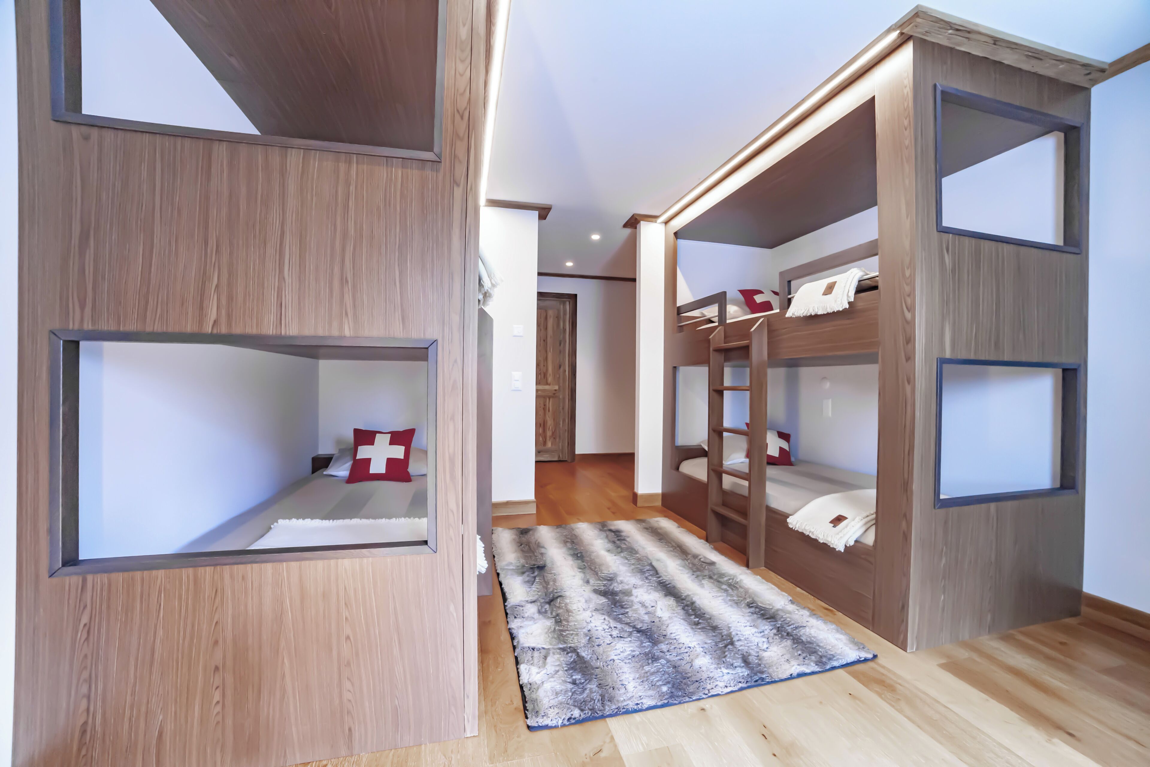 Ein Zimmer mit Etagenbetten, Holzboden und Teppich.