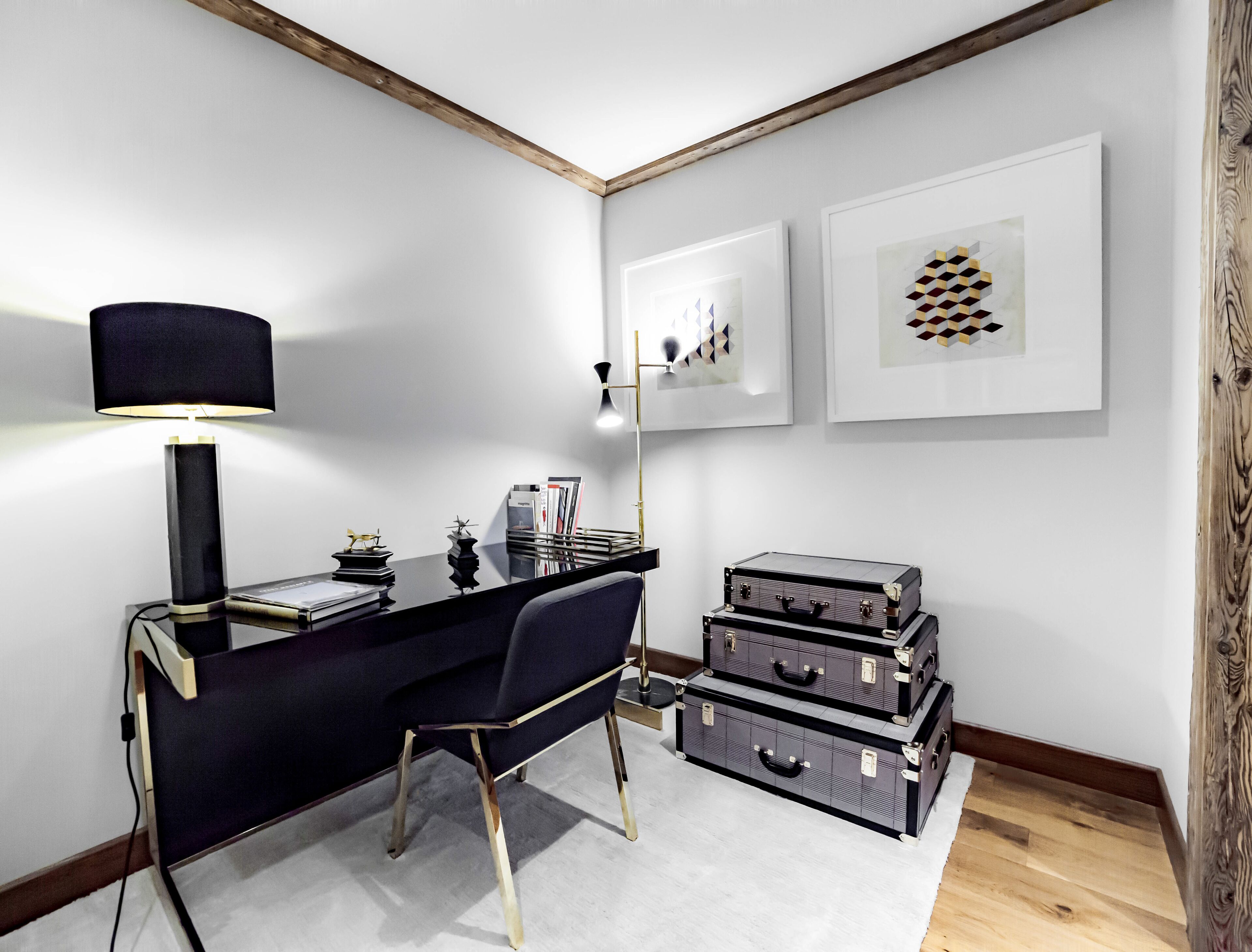 A modern office space with a desk, chair, lamp, and wall-mounted artwork.