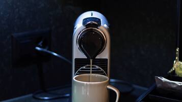 A Krups coffee maker on a dark countertop with a white mug underneath.