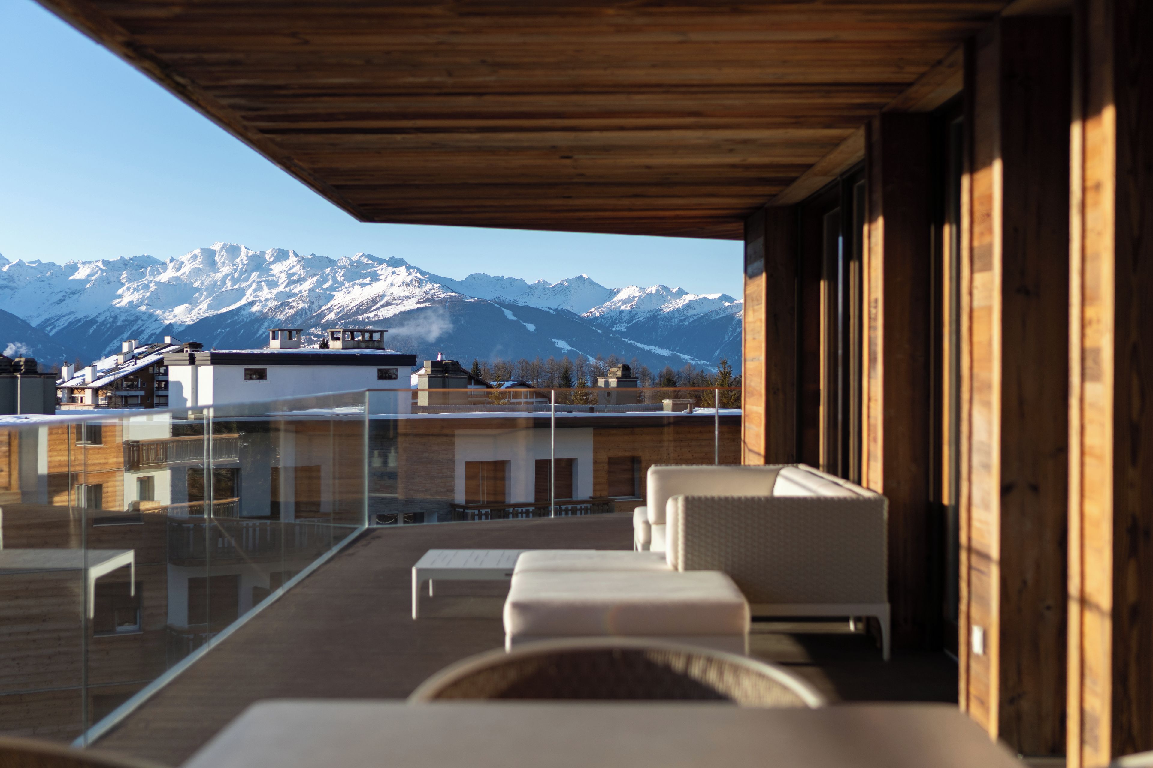 Un espace extérieur moderne, aménagé pour se détendre, avec vue sur des montagnes enneigées.