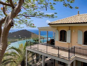 A two-story building with a balcony overlooking a coastal view.