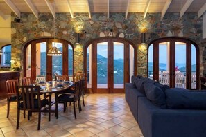 A dining area with a stone wall, wooden doors, and a view of the mountains.