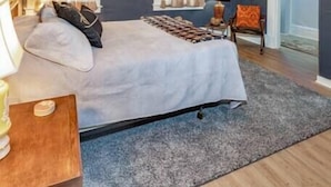 A bedroom with a bed, a ceiling fan, a chair, and a door.