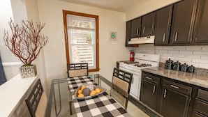 A kitchen with a checkered table, dark cabinets, and a stove.