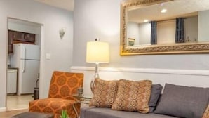 A living room with a grey sofa, patterned cushions, a wooden coffee table, and a mirror with a gold frame.