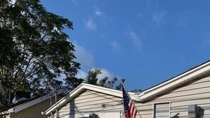 A single-story mobile home with a front porch, an American flag, and two chairs. - Refined Studio, New Construction, 1 Mile From Town (Pittsburgh)