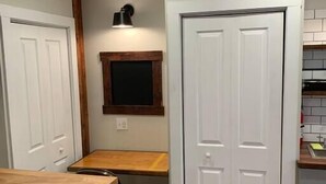 A compact kitchen with a wooden table, a built-in bench, and a white double door. - Refined Studio, New Construction, 1 Mile From Town (Pittsburgh)