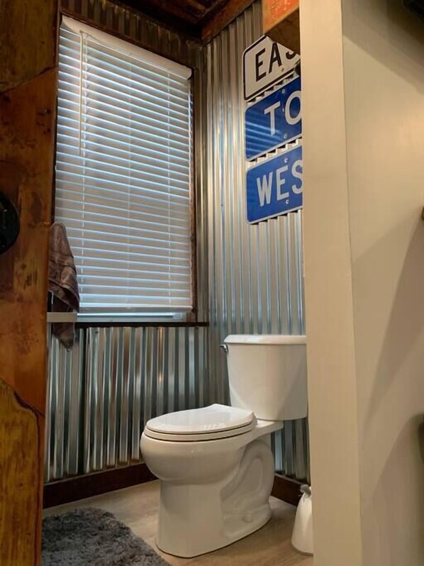 A bathroom with a toilet, a window with blinds, and a sign above the toilet. - Refined Studio, New Construction, 1 Mile From Town (Pittsburgh)
