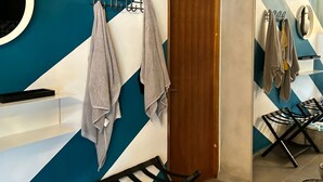 Un bagno dal design moderno, con uno specchio grande, una porta in legno e un angolo relax con una sedia e un tavolino.
