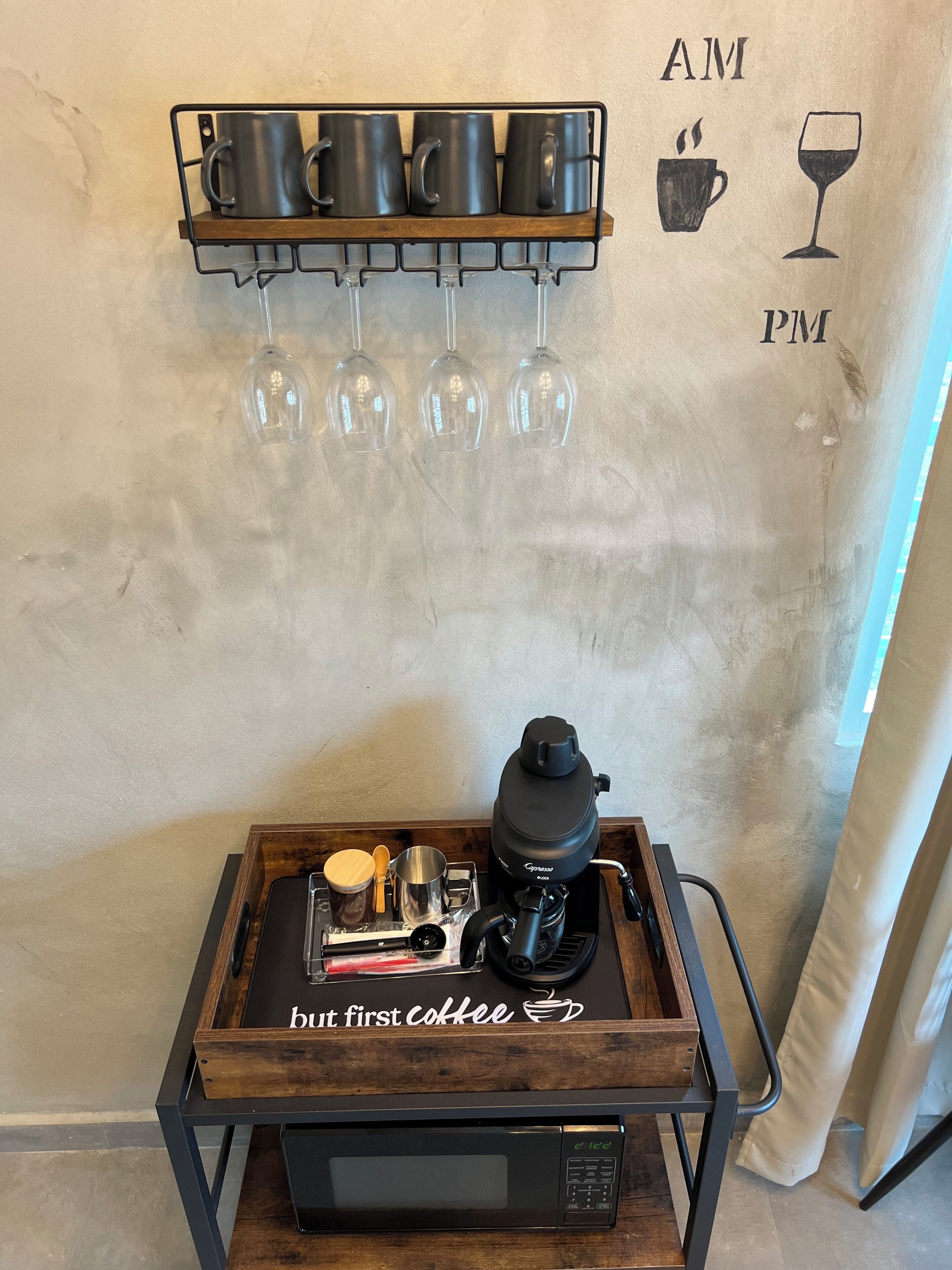 Eine Kaffeestation mit Kaffeemaschine, Tassen und Gläsern auf einem Holztablett.