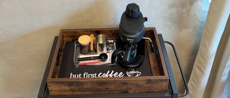Un coin café comprenant une machine à café, des tasses et des verres, le tout disposé sur un plateau en bois.