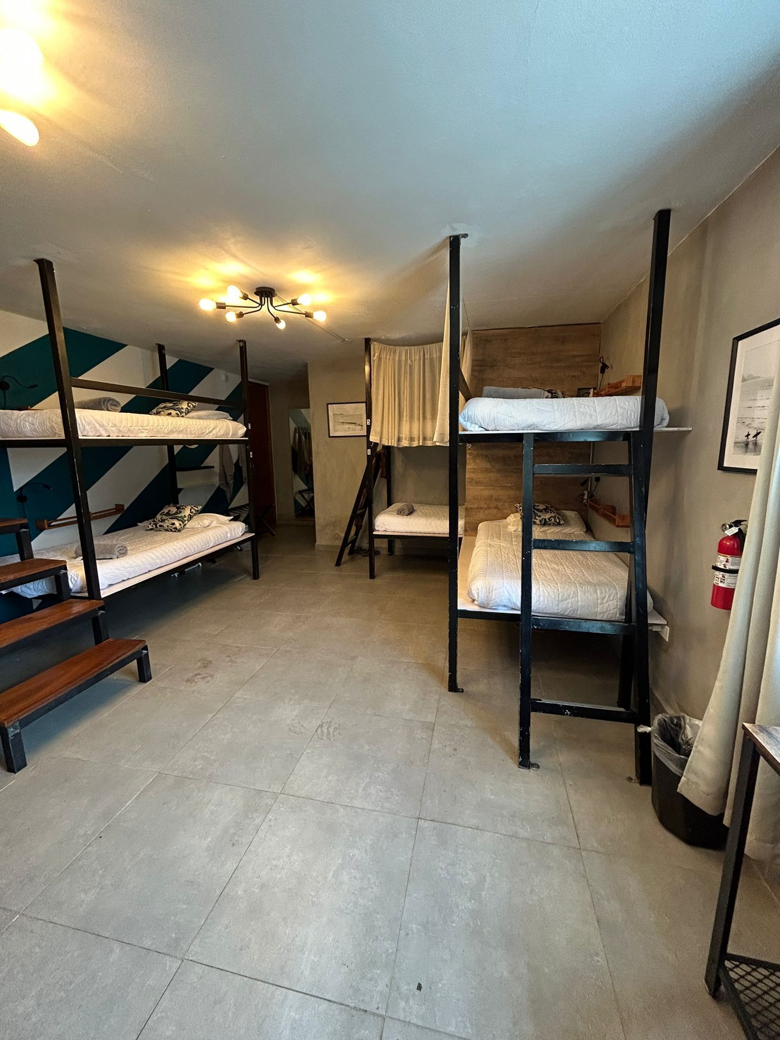 A dormitory-style room with bunk beds, a tiled floor, and a ceiling light fixture.