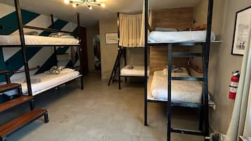 A dormitory-style room with bunk beds, a tiled floor, and a ceiling light fixture.