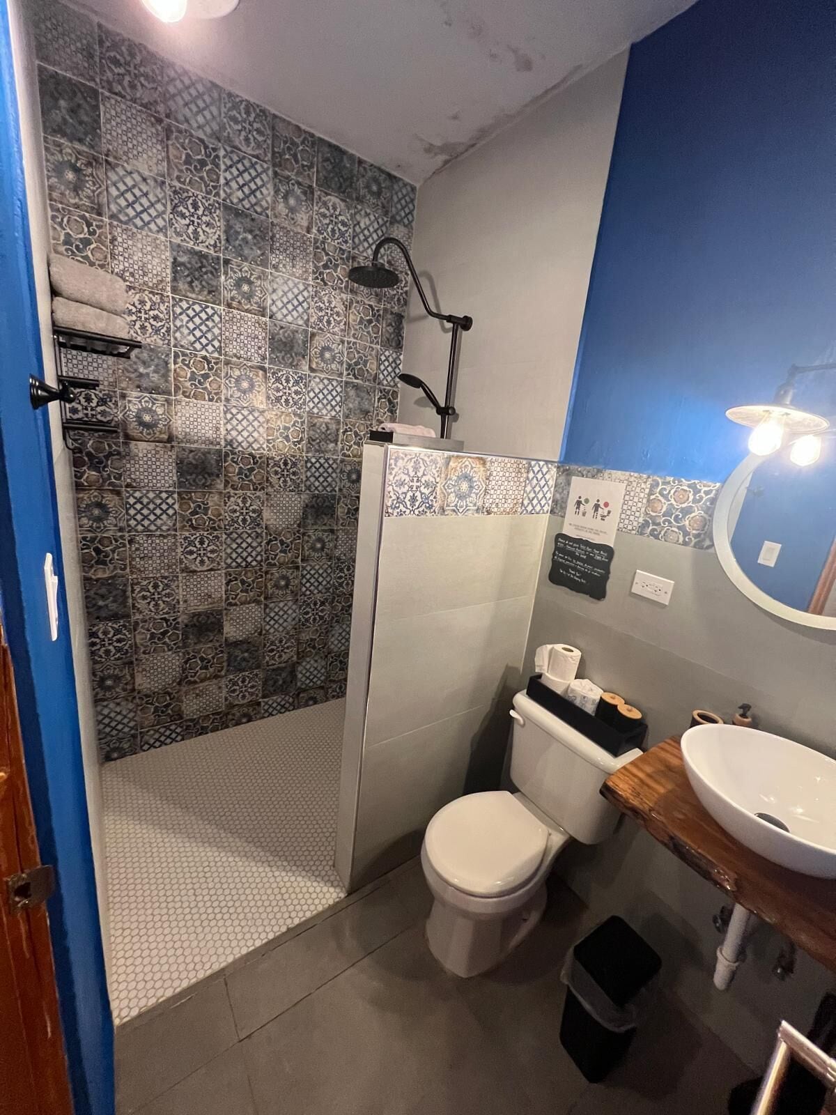 A bathroom with a shower, toilet, sink, and a mirror.