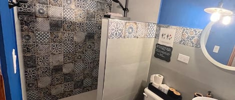 A bathroom with a shower, toilet, sink, and a mirror.
