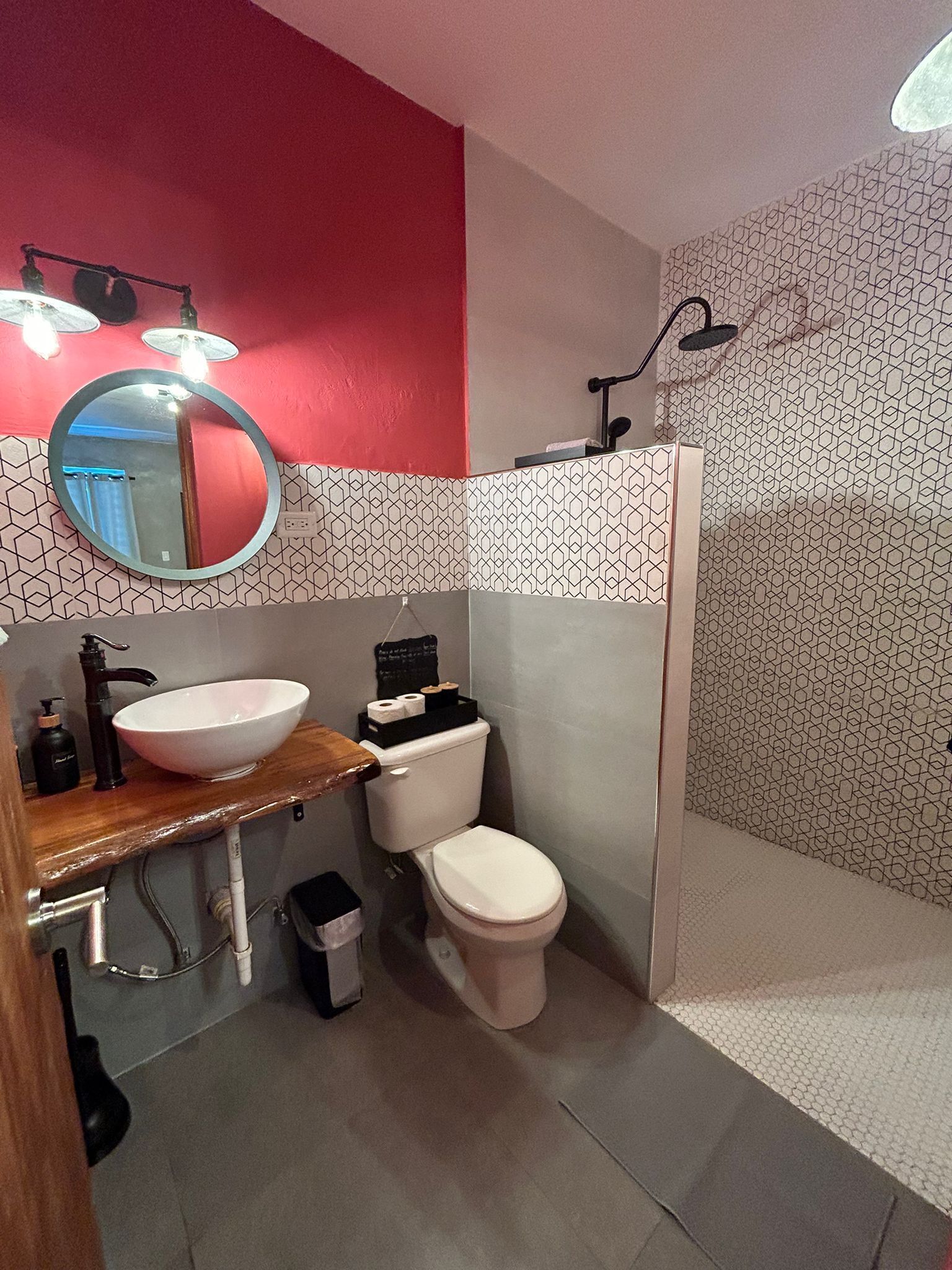 A bathroom with a wooden vanity, a white sink, a toilet, and a shower area.