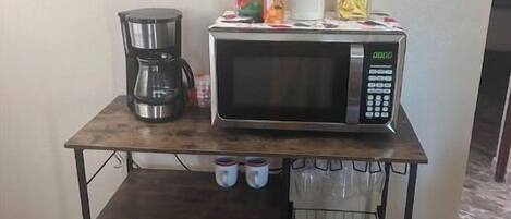 Eine Küchenarbeitsplatte mit Kaffeemaschine, Mikrowelle und verschiedenen Behältern.