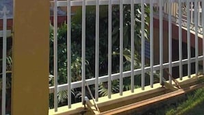 A yellow building with a red roof, white fencing, and a palm tree in the background. - Private Country house 5 miles from beach (Aguada)