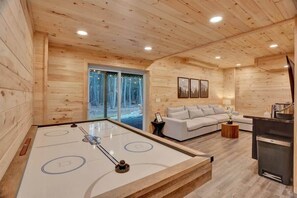 Un interior de madera con mesa de juego de discos, sofá y zona de cocina.