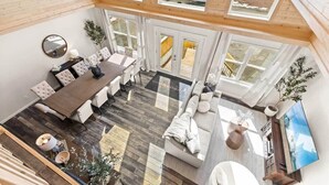 Amplia habitación tipo loft con zona de comedor, asientos y un gran ventanal.