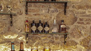 A bar area with shelves of various alcoholic beverages and glasses. - OPUS 1910 OTEL (Ayvalik)