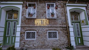 A historic building with a stone facade, green doors, and windows with white frames. - OPUS 1910 OTEL (Ayvalik)