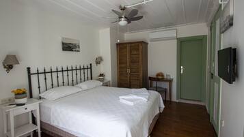 Un dormitorio con cama, mesita de noche, armario de madera, puerta verde y ventilador de techo.
