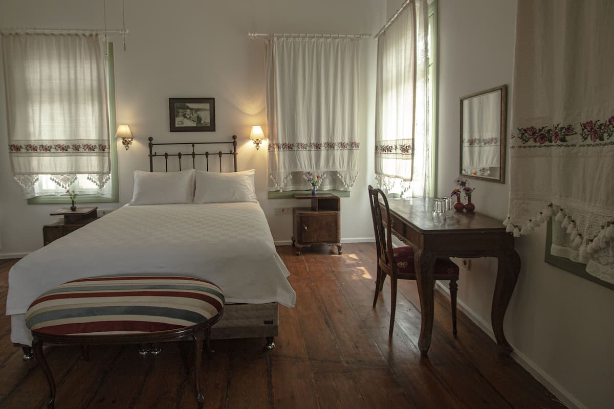 A bedroom with a large bed, bedside tables, a desk, and a chair.