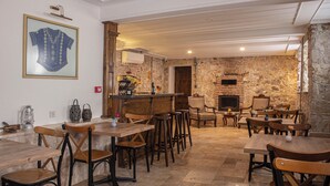 A rustic interior with stone walls, wooden furniture, and a bar area. - OPUS 1910 OTEL (Ayvalik)