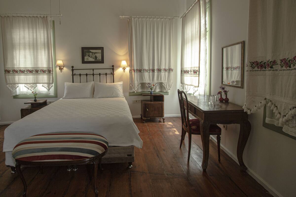 A bedroom with a bed, bedside tables, a desk, and a chair.