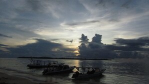 Boats docked at a calm waterfront during sunset. - De Padma Villa Gili Air (Gili Air)