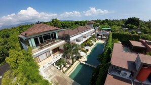 A resort with multiple swimming pools, a large outdoor area with seating, and a view of the mountains. - De Padma Villa Gili Air (Gili Air)