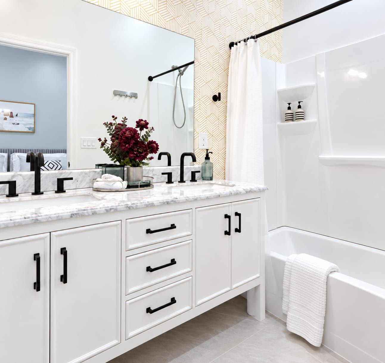 Une salle de bain moderne avec un meuble-lavabo blanc, un grand miroir, une douche et un porte-serviettes.