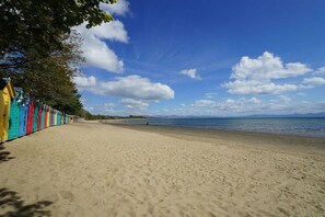 A beach with a row of colorful beach huts along the shore. - Greenacres - Two Bedroom Cottage, Sleeps 4 (Llanbedrog)