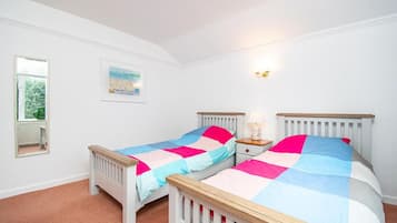 Un dormitorio con dos camas individuales, una mesita de noche, una lámpara, una ventana y un cuadro en la pared.
