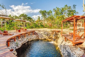 A wooden deck with lounge chairs and a small waterfall.