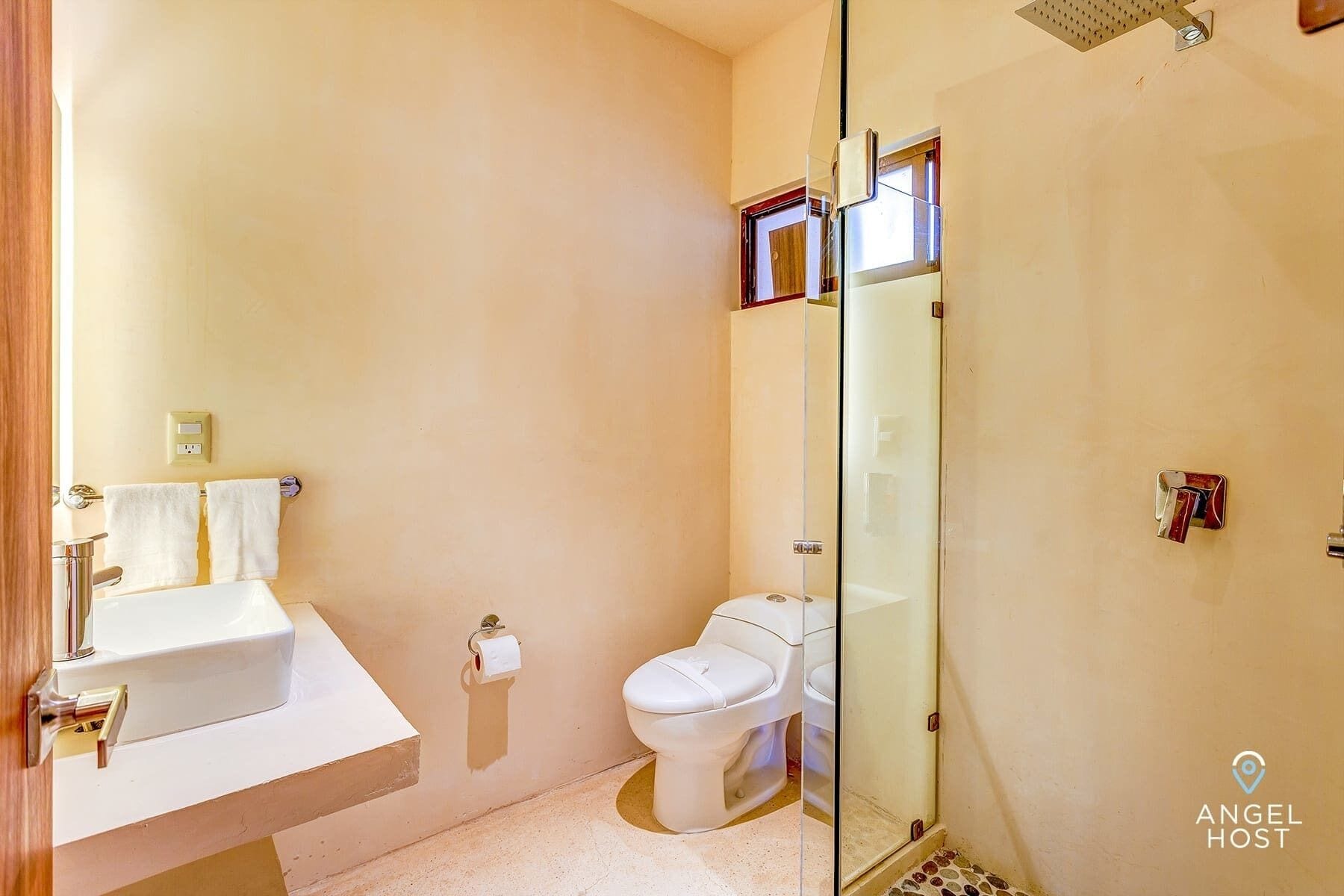Een badkamer met een wit wastafelmeubel, toilet en een douchecabine van glas.