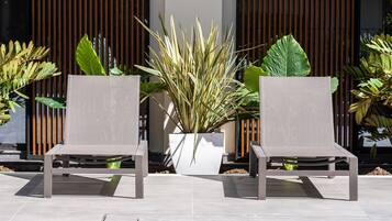 Zwei Terrassenstühle mit einem Blumentopf dazwischen.