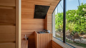 Un cuarto de sauna con paredes de madera, una ventana y un banco de madera.