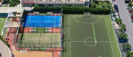 An aerial view of a sports complex with multiple fields, including a soccer field, tennis courts, and a basketball court.
