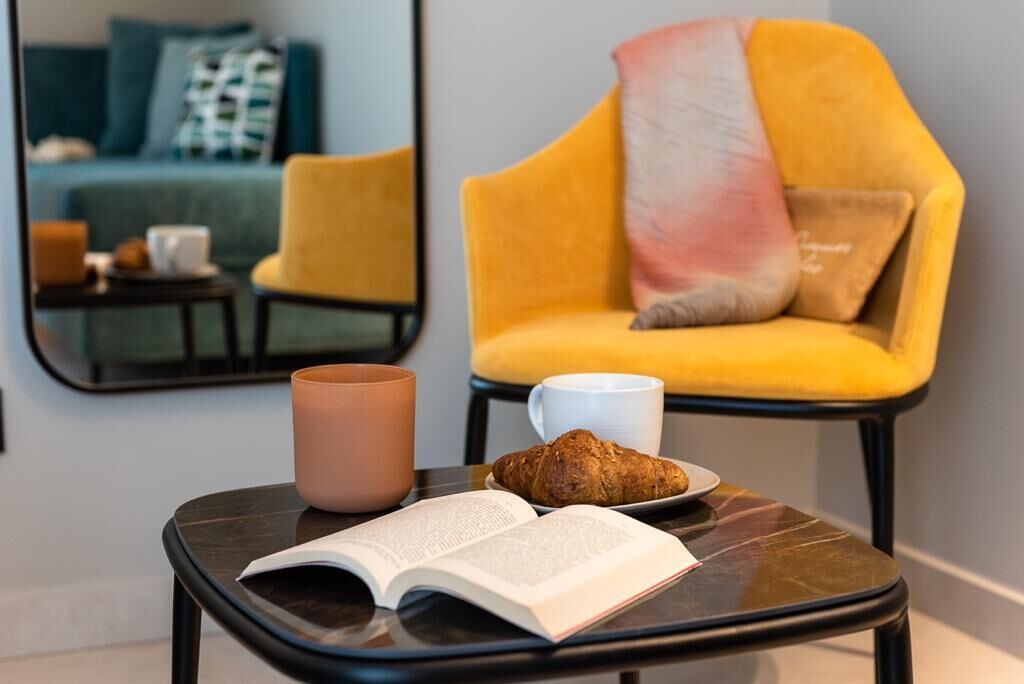 Eine gemütliche Leseecke mit einem kleinen Tisch, einem Buch, einem Croissant und einer Tasse.